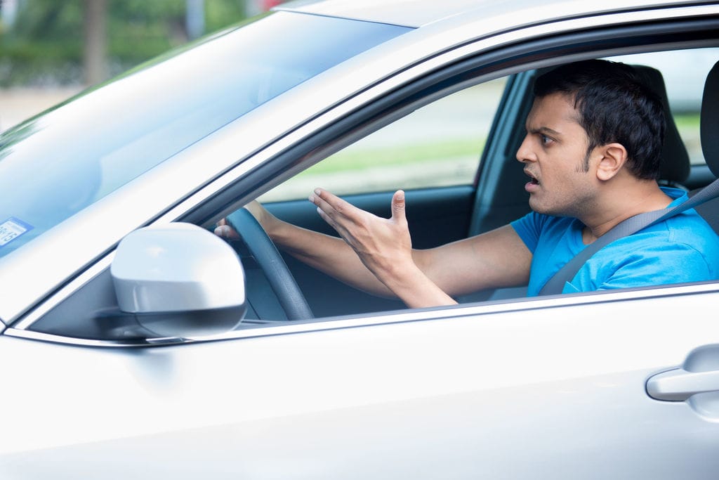man in car with head jutting forward and angry look on face