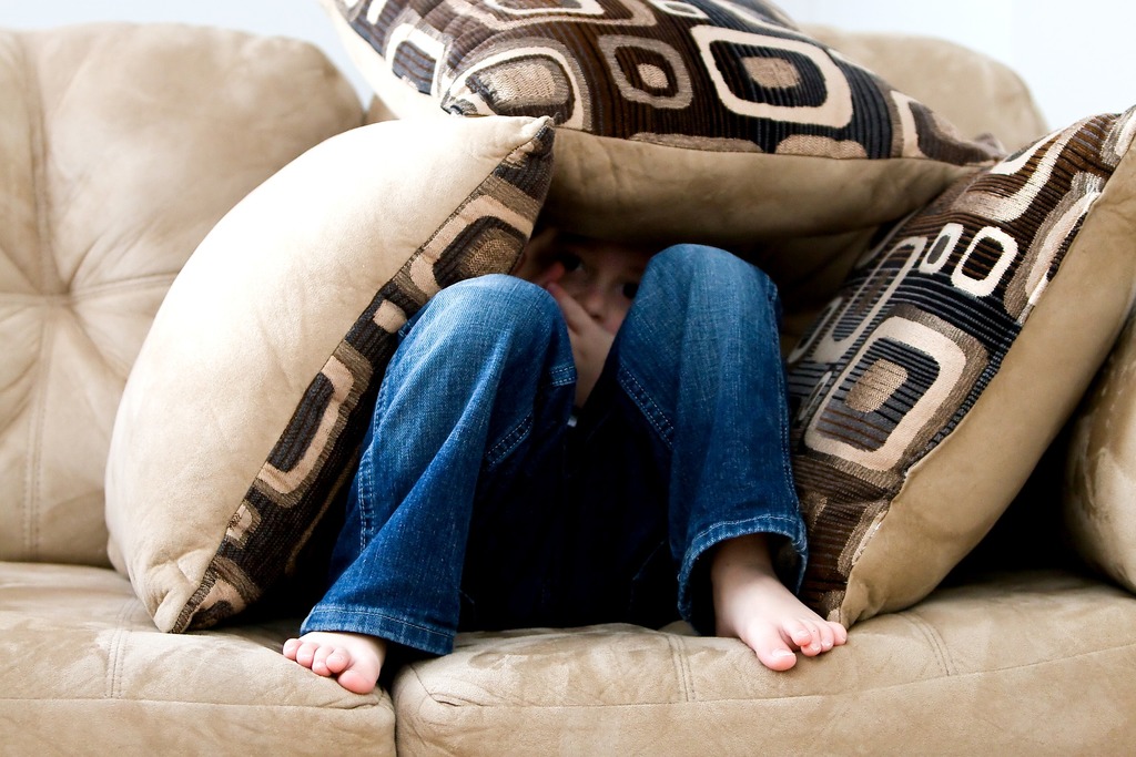 little boy hiding under the couch afraid
