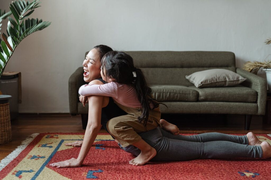 woman doing embodiment exercise with daughter on her back