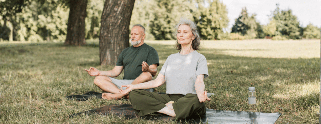 a man and a woman resting and meditating in an open field