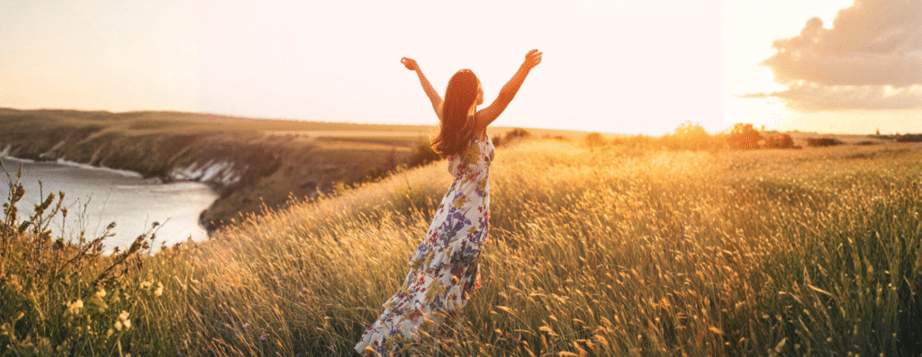 A woman raising her arms enjoying the sunlight