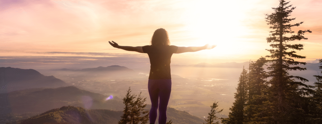 A woman spreading her arms looking at the mountain view