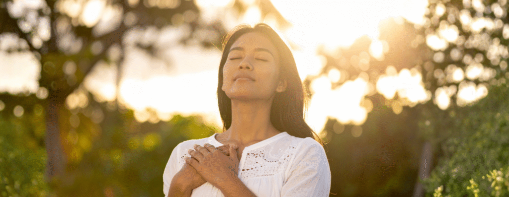 A woman meditating in the forest feeling free